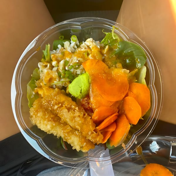 Big Bang Sushi & Poke bowl with tempura, mango, avocado, and greens in a plastic container.