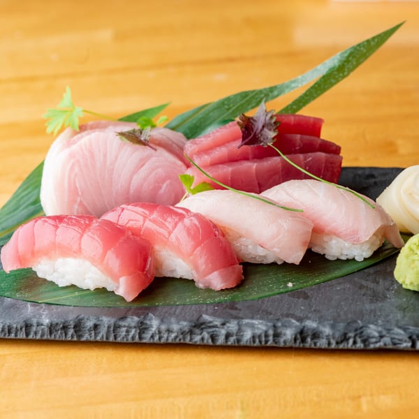 Assortment of Big Bang Sushi & Poke tuna and yellowtail nigiri and sashimi on a dark plate.
